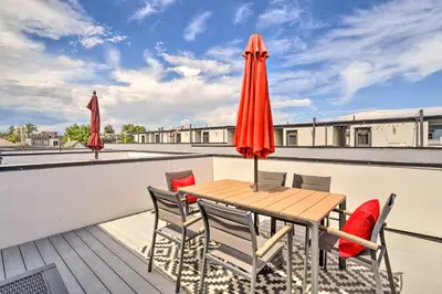 a wooden table and chairs on a balcony with an umbrella at City Skyline Views Upscale Denver Townhome in Denver