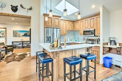 a kitchen with wooden cabinets and blue bar stools at Winter Park Condo with Mountain Views and Hot Tub in Winter Park