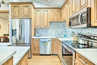 a kitchen with wooden cabinets and a stainless steel refrigerator at Winter Park Condo with Mountain Views and Hot Tub in Winter Park