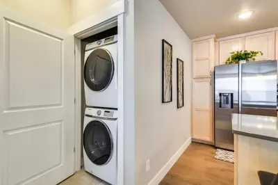 a kitchen with a washer and dryer next to a refrigerator at Elegant Loveland Condo Less Than 5 Mi to Old Town! in Loveland
