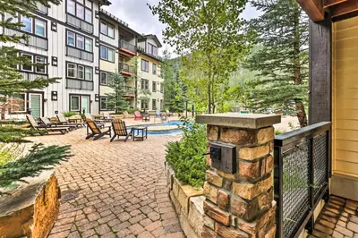 a patio with a stone wall and a fence at Charming Winter Park Condo - Steps to Slopes! in Winter Park