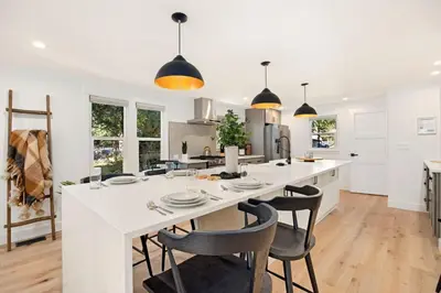 a kitchen with a large white island with chairs at Elegant Old Town Charm - Walk to CSU and Downtown in Fort Collins