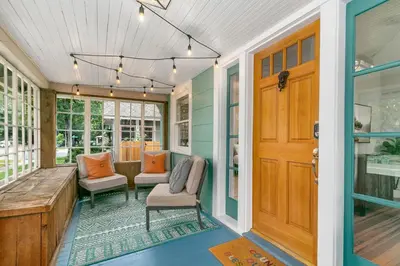 a porch with a wooden door and chairs at Downtown Abode with Hot Tub - Walk to CSU & Old Town in Fort Collins