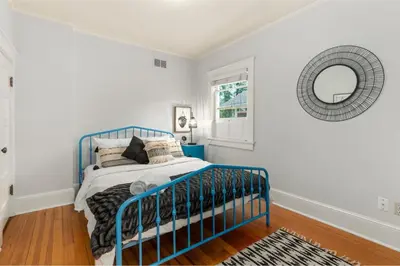 a blue bed in a white room with a mirror at Downtown Abode with Hot Tub - Walk to CSU & Old Town in Fort Collins
