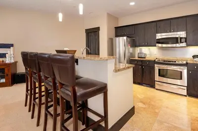 a kitchen with a bar with stools in it at Parry Peak Loft Premium-Rated 105 in Winter Park