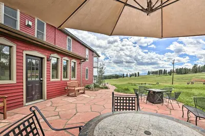 a patio with a table and chairs and an umbrella at Mtn View and Group Ready Conifer Home on 100 Acres! in Conifer