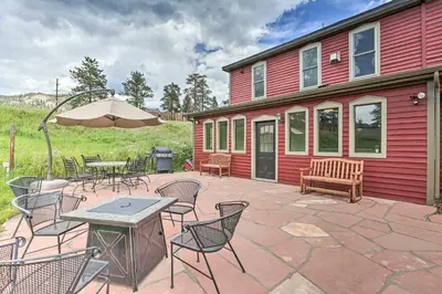 a patio with tables and chairs and an umbrella at Mtn View and Group Ready Conifer Home on 100 Acres! in Conifer