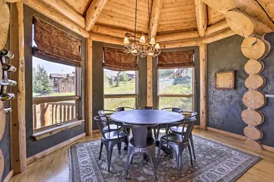 a dining room with a table and chairs and windows at Skiing and Hiking Access Spacious Granby Cabin! in Granby