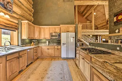 a kitchen with wooden cabinets and a refrigerator at Skiing and Hiking Access Spacious Granby Cabin! in Granby