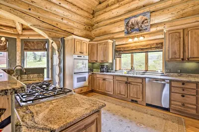 a kitchen with wooden cabinets and a stove top oven at Skiing and Hiking Access Spacious Granby Cabin! in Granby