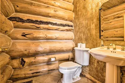 a bathroom with a wooden wall with a toilet and a sink at Skiing and Hiking Access Spacious Granby Cabin! in Granby