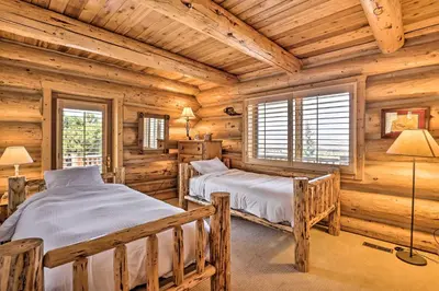 two beds in a log cabin bedroom with wooden walls at Skiing and Hiking Access Spacious Granby Cabin! in Granby