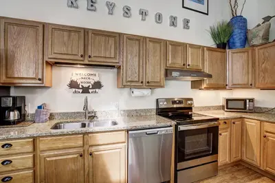 a kitchen with wooden cabinets and stainless steel appliances at Luxury 2 Bedroom Condo with Pool Hot Tub and Sauna in Keystone
