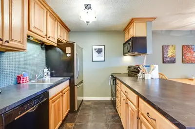 a kitchen with wooden cabinets and a black appliances at Silverthorne Condo with Lake Views 10 Mi to Skiing! in Silverthorne