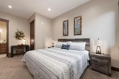 a bedroom with a bed and a table with a lamp at Elk Creek Condos B103 by Stay Winter Park in Fraser