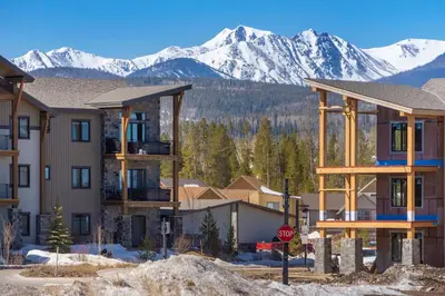 a group of buildings with snow capped mountains in the background at Elk Creek Condos B103 by Stay Winter Park in Fraser