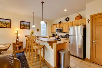 a kitchen with a stainless steel refrigerator and wooden cabinets at Ski and Explore Silverthorne Gem with Hot Tub Access! in Silverthorne