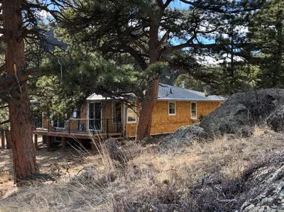 a wooden house with a porch and a tree at Hot Tub! Pets Ok! Perfect Estes Park Getaway, Walk to Town 3 Kings!#3337 in Estes Park