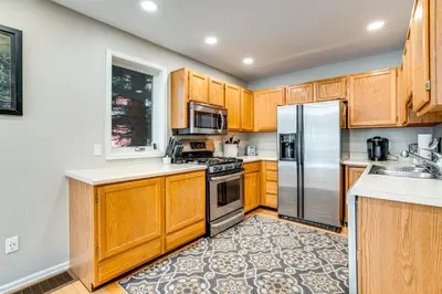 a kitchen with wooden cabinets and stainless steel appliances at Less Than 1 Mi to Dtwn Creekside Frisco Home with Fire Pit in Frisco