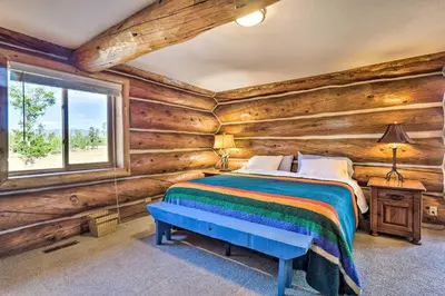 a bedroom with wooden walls and a bed with a blue bench at Less Than 1 Mi to Lake Granby Log Cabin with Fire Pit in Grand Lake