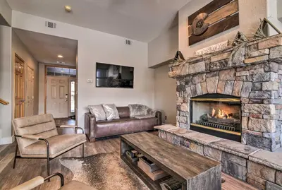 a living room with a large stone fireplace at 7 Mi to Keystone Waterfront Home with Scenic Views in Silverthorne