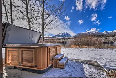 a hot tub sitting on a snow covered porch with mountains at 7 Mi to Keystone Waterfront Home with Scenic Views in Silverthorne