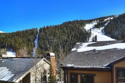 a house with a snow covered mountain in the background at Slopeside in Keystone
