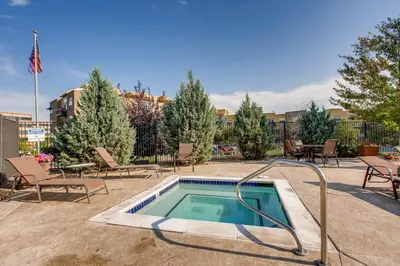 a swimming pool with chairs and a table and a flag at Mountain Views Luxury Condo in the DTC in Centennial