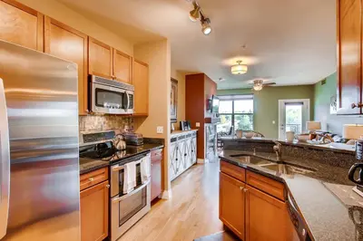 a kitchen with wooden cabinets and a stainless steel refrigerator at Mountain Views Luxury Condo in the DTC in Centennial