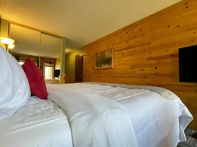 a bedroom with a white bed with a wooden wall at Relax, Adventure, Views, Amenities+Memories (Full) in Granby
