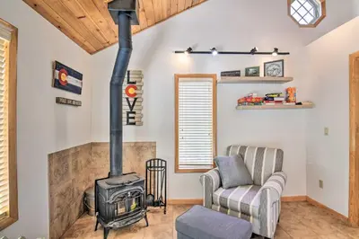 a living room with a wood stove and a couch at 4 Mi to Grand Lake Mtn-View Cabin with Fire Pit! in Grand Lake
