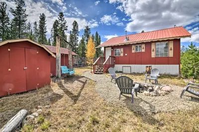 a red house with chairs in front of it at 4 Mi to Grand Lake Mtn-View Cabin with Fire Pit! in Grand Lake
