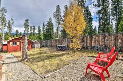a red bench sitting in a yard with a fence at 4 Mi to Grand Lake Mtn-View Cabin with Fire Pit! in Grand Lake