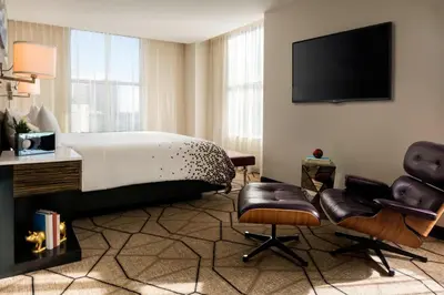 a bedroom with a bed and two chairs and a television at Renaissance Denver Downtown City Center Hotel in Denver