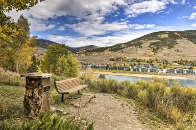 a wooden bench sitting on the side of a river at Lakefront Condo with Mtn Views in Dillon! in Dillon