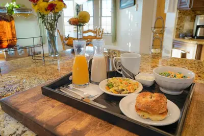 a tray of food with a sandwich and salad and orange juice at Summit Villa BnB in Watkins
