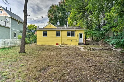 a yellow house in a yard next to a house at Charming Fort Collins Home By Old Town and CSU! in Fort Collins