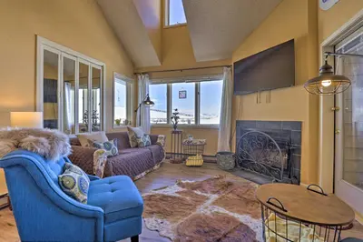 a living room with a blue couch and a fireplace at Cozy Ski-InandSki-Out Granby Condo with Balcony! in Granby