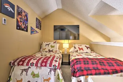 a room with two beds and a tv on the wall at Cozy Ski-InandSki-Out Granby Condo with Balcony! in Granby
