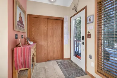 a hallway with a wooden door and a table and a window at Panoramic View Home with Hot Tub & Game Room in Black Hawk