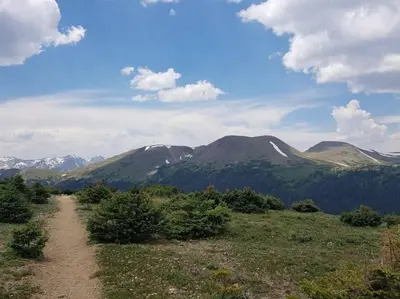 a dirt road in a field with mountains in the background at Sundance-2 miles to Rocky Mountain National Park in Estes Park