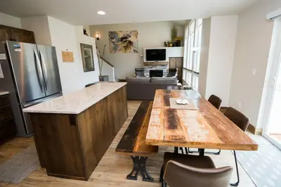 a kitchen with a large wooden table and a living room at Sundance-2 miles to Rocky Mountain National Park in Estes Park