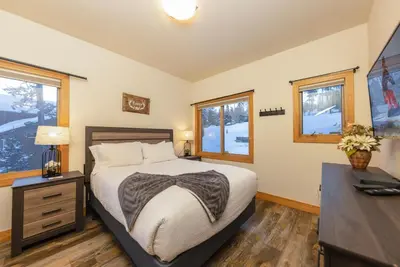 a bedroom with a bed and a desk and windows at Beautiful 7 BEDROOM, 3 gathering areas, pool table, hot tub, and huge deck with 360-degree views!! in Silverthorne