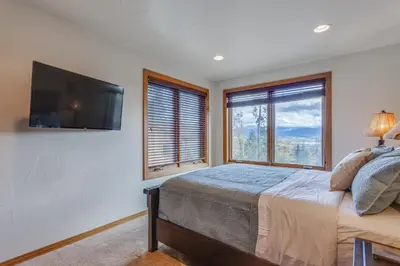 a bedroom with a bed and a flat screen tv at Beautiful 7 BEDROOM, 3 gathering areas, pool table, hot tub, and huge deck with 360-degree views!! in Silverthorne