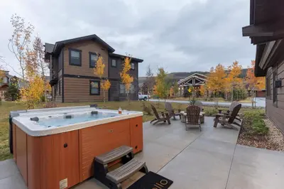 a hot tub on a patio next to a house at LUXURY HOME by the river! Walk to Shuttle, Hot Tub, Fire Pit, designer finishes!! in Breckenridge