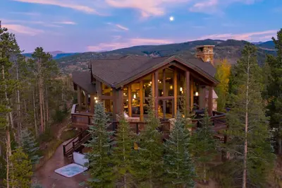 a large house in the woods with a mountain at Four master suites, VIEWS!! Hot tub, private ski SHUTTLE, sprawling entertaining areas!! in Breckenridge