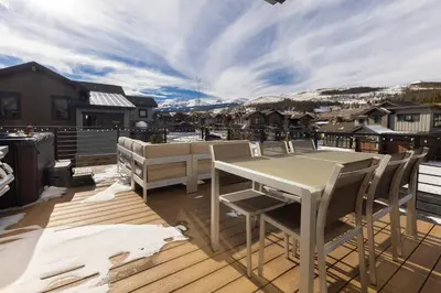 a patio with a table and chairs on a deck at Modern Elegance, Stunning Mountain Views, Hot Tub, Fire Pit, Walk to River! in Breckenridge