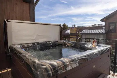 a hot tub sitting on a balcony with at Modern Elegance, Stunning Mountain Views, Hot Tub, Fire Pit, Walk to River! in Breckenridge