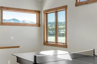 a ping pong table in a room with two windows at Fraser Wonder in Fraser
