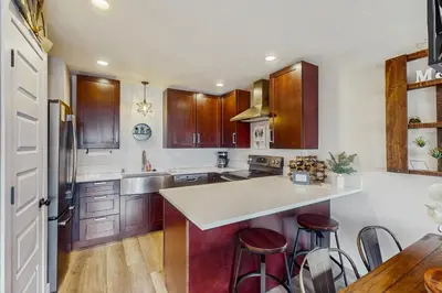 a kitchen with wooden cabinets and a kitchen island with stools at Winter Park Lodge II #104 in Fraser